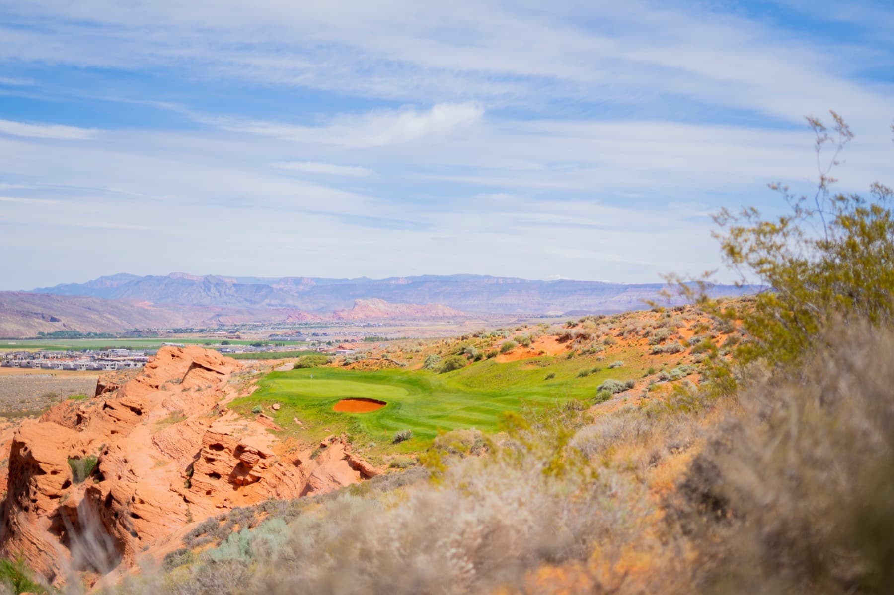 A red rock golf hole with a green tucked into the desert landscape.